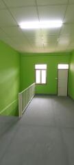 Spacious empty room with green walls, fluorescent lighting and wooden door