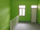 Spacious empty room with green walls, fluorescent lighting and wooden door