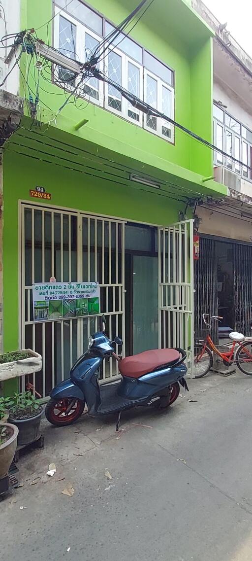 Exterior view of a lime green two-story building with security gate