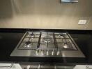Modern kitchen with stainless steel gas stove and black countertop
