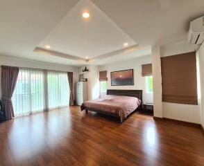 Spacious bedroom with king-sized bed, wooden floors, and ample natural light