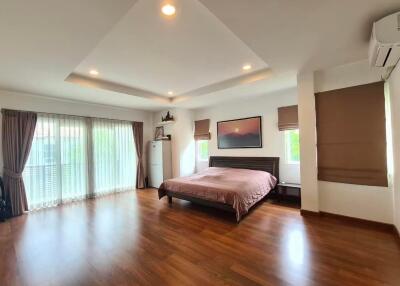 Spacious bedroom with king-sized bed, wooden floors, and ample natural light