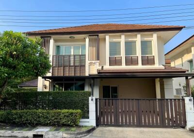 Two-story suburban house with a brown gate and a clear sky