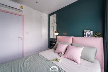 Cozy bedroom with modern decor, mint and pink accents, and built-in storage