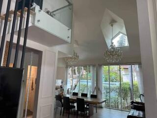 Spacious double-height dining room with large windows and modern chandeliers