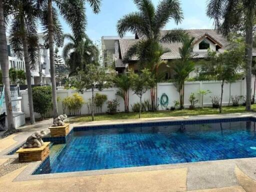 Private swimming pool with house and garden in the background