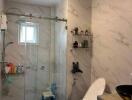 Modern bathroom with marble walls and glass shower enclosure