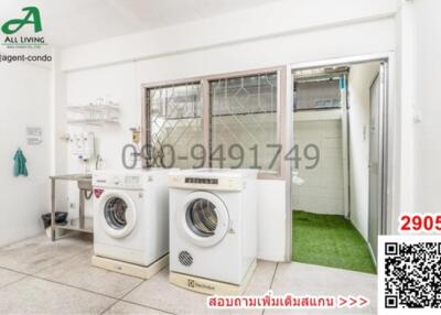 Compact laundry room with white walls, washing machines, and access to outdoor area