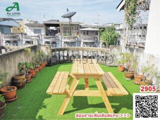 Cozy patio space with wooden picnic table and green artificial turf surrounded by potted plants