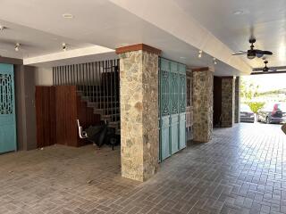 Spacious covered parking area with stone columns and a staircase leading to upper levels