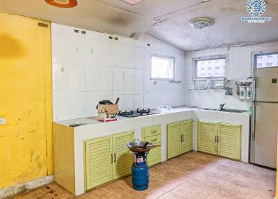 Spacious but in need of renovation kitchen with yellow cabinets and white tiles
