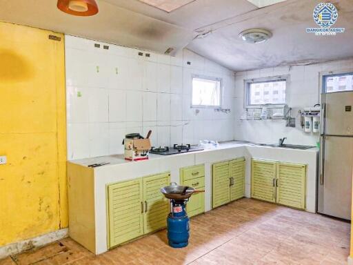 Spacious but in need of renovation kitchen with yellow cabinets and white tiles