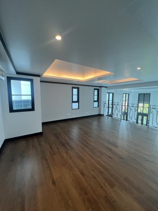 Spacious and well-lit empty interior room with wooden flooring and multiple windows