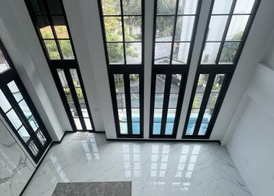 Bright foyer with large windows and marble flooring by a pool