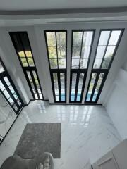 Bright foyer with large windows and marble flooring by a pool