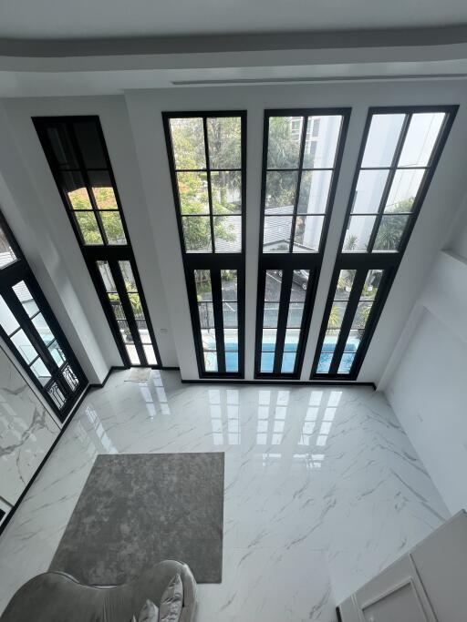 Bright foyer with large windows and marble flooring by a pool
