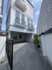 Exterior view of a modern white residential building with balcony and parking space