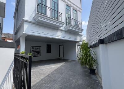 Exterior view of a modern white residential building with balcony and parking space