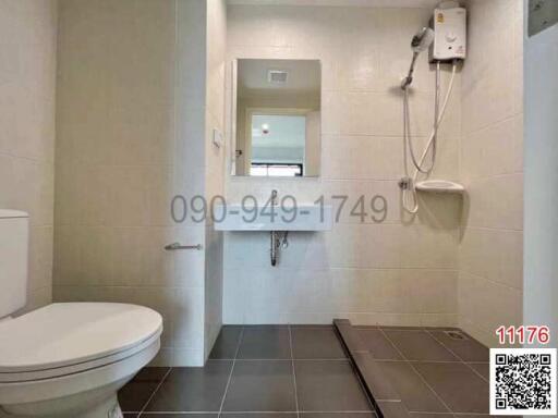 Compact bathroom with white fittings, including a toilet, shower, and water heater