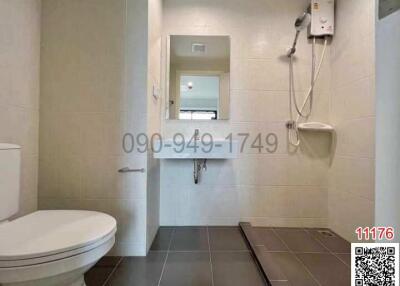 Compact bathroom with white fittings, including a toilet, shower, and water heater