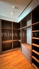 Spacious walk-in closet with empty shelves and wooden flooring