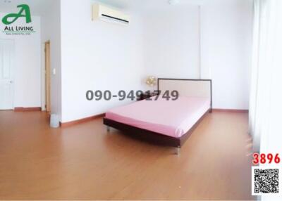 Spacious bedroom with wooden flooring and air conditioning unit