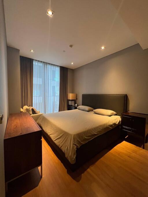 Modern bedroom with large bed, wooden furnishings, and ample lighting