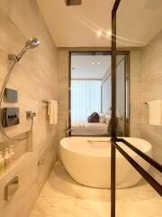 Modern bathroom with a freestanding bathtub and a view into a bedroom.