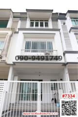 Contemporary multi-story residential townhouse with white facade and gated entrance