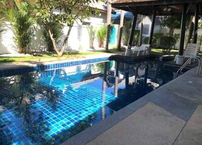 Residential swimming pool with sun loungers and landscaped garden