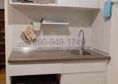 Compact kitchen space with white cabinetry and stainless steel sink