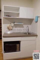 Compact kitchen space with white cabinetry and stainless steel sink