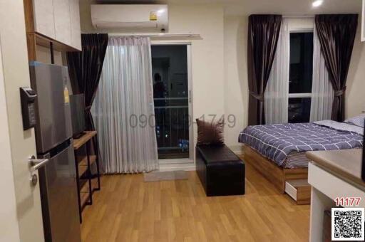 Compact bedroom with integrated living space including bed, television, and balcony access