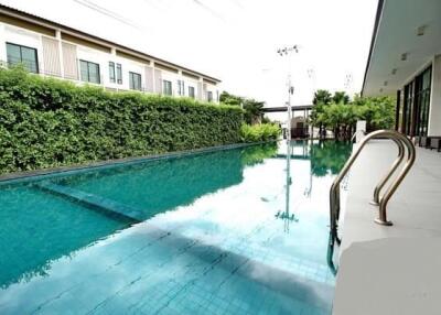Residential swimming pool alongside row of townhouses with lush green hedge