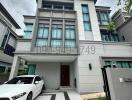 Modern two-story residential building with front yard and white car parked outside