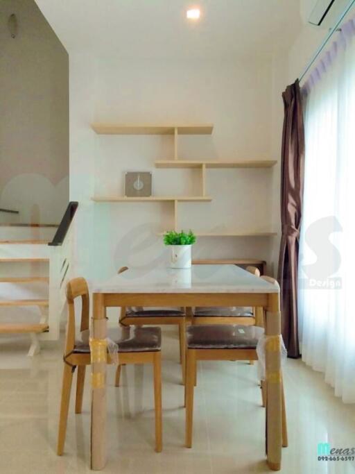 Cozy dining area with wooden table and chairs, stylish shelves on the wall, and staircase leading to another level