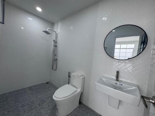 Modern bathroom with white tiles, pedestal sink, and shower area