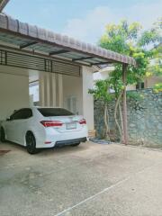 Residential carport with vehicle and stone wall