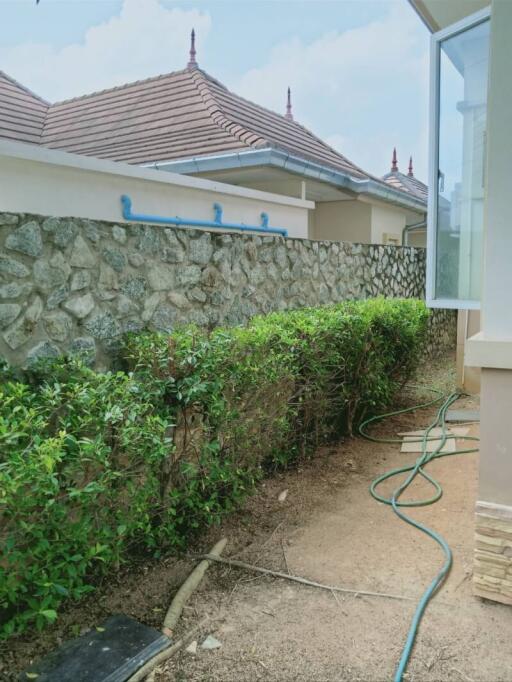 Exterior view of a house with stone detail and garden space