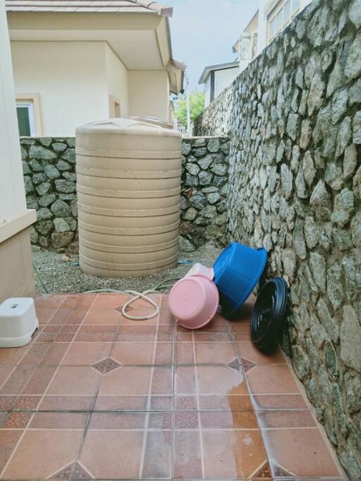 Tiled outdoor area with a water tank and plastic items