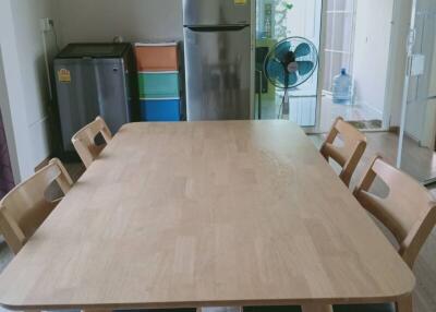 Spacious kitchen with wooden dining table, chairs, refrigerator and a fan