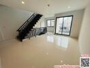 Spacious living room with large windows and a staircase