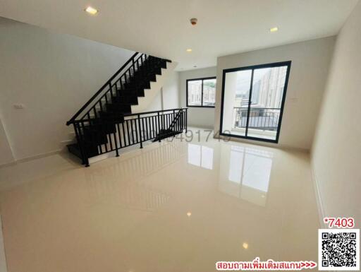 Spacious living room with large windows and a staircase