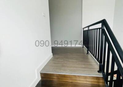 Spacious staircase with wooden steps and black handrails