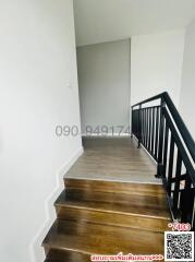 Spacious staircase with wooden steps and black handrails