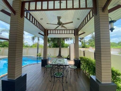 Covered patio area with swimming pool view, ceiling fan, and outdoor dining set