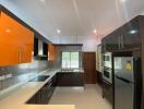 Modern kitchen with orange cabinets and stainless steel appliances