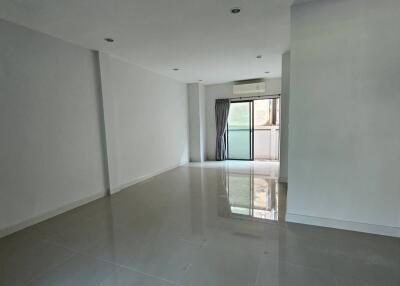 Spacious and brightly lit living room with glossy floor and glass door leading to a balcony