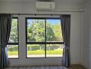 Bright bedroom with large windows and an air conditioning unit