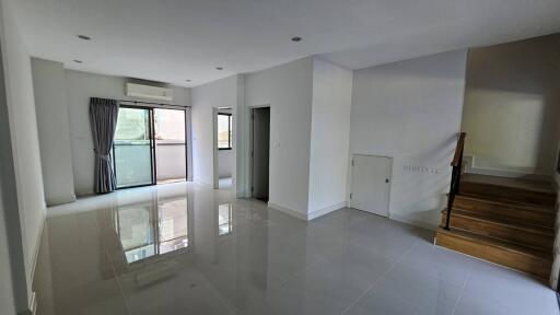 Spacious and brightly lit living room with staircase and sliding glass door